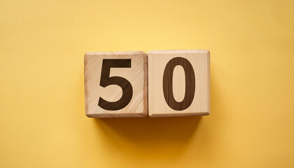 Wall Mural - Wooden cubes with number 50 on isolated yellow backdrop. Wood blocks. Close-up. Flat lay