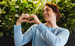 © Jacob Lund - Showing love for sustainability: Business woman displays a heart gesture in a green office