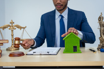 An Asian businessman in a formal suit works alone at a lawyer's desk, with golden scales, law books, leather bags, and a Lady Justice statue, emphasizing personal freedom and legal matters.