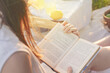 © Vladimir Razgulyaev - A woman finds peace and relaxation in nature while reading a book outdoors on a sunny day