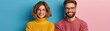 © pisan - Couple Posing with Humorous Gesture in Matching Sweaters, Ready for a Photo Shoot Against a Blue and Pink Background