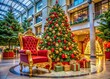 © Man888 - Colorful festive holiday scene of a decorated Christmas tree and ornate throne waiting for jolly old Saint Nick in a bustling shopping center setting.