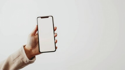 female hand with white sweater holding modern phone in vertical position with empty screen on white background. Mockup easy to edit