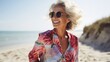 © venusvi - Smiling senior woman in stylish dress enjoying a walk on the beach