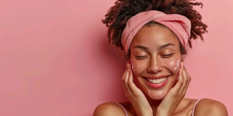 A smiling woman wearing a pink towel on her head for sun protection or as a hair accessory