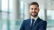 © Elena - Portrait of a confident businessman in a suit standing in a modern office building..Professional attire and confident expression in a corporate office environment, ideal for business themes.