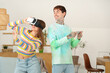 © Pixel-Shot - Young man with mobile phone and his girlfriend using VR glasses at home