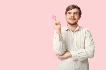 Poster - Young man with credit card on pink background