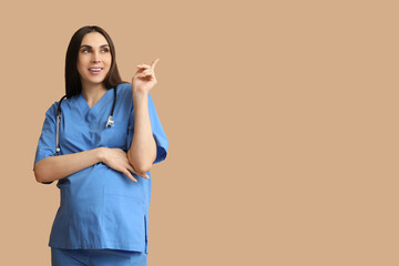 Poster - Beautiful young pregnant doctor pointing at something on brown background