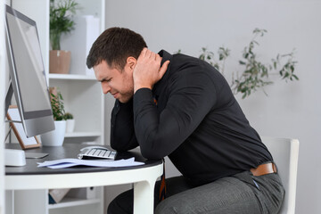 Canvas Print - Young businessman suffering from neck pain at table in office