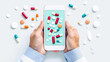 © WinThing - Hands holding smartphone displaying various colorful pills, surrounded by scattered tablets and capsules on white background.