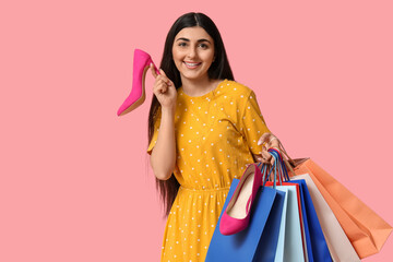 Wall Mural - Happy smiling young woman with shopping bags and shoes on pink background