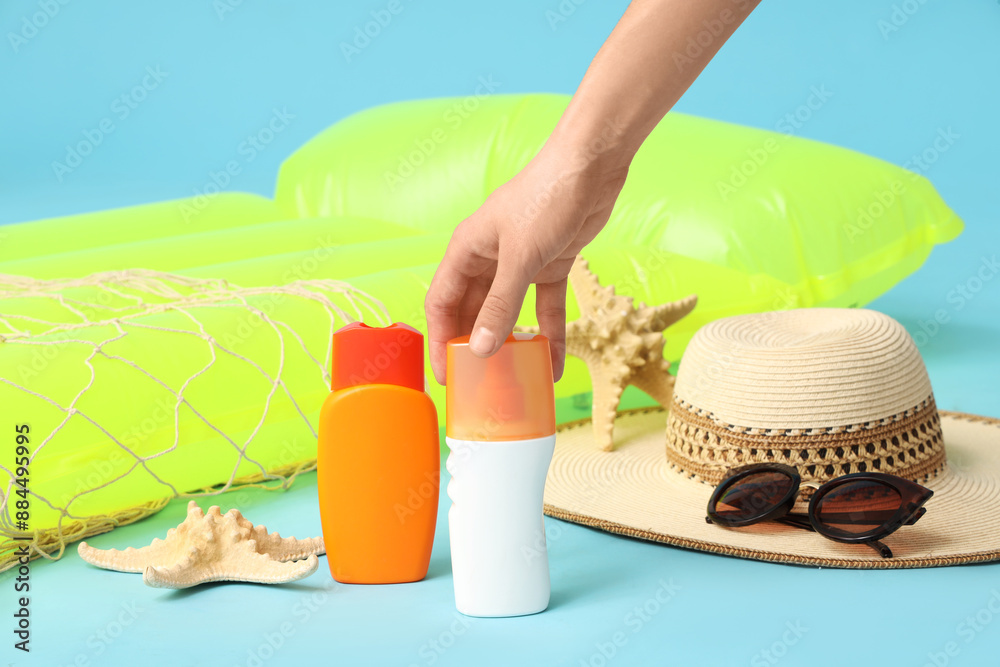Female hand taking sunscreen spray on blue background