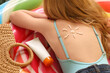 © Pixel-Shot - Beautiful girl with sunscreen cream on her back in shape of sun lying on inflatable mattress. Closeup