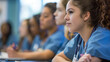 © Maksym - Student nurses attentively listening to an instructor, taking notes during a clinical skills training session at their college.