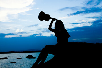 Canvas Print - happy girl with ukulele by the sea on nature silhouette background