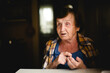 © De Visu - An elderly woman sits at the table, counting on her fingers as she tells a story.
