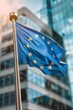 © Margarita Ratatosk - Flag of European Union waving in the wind in front of the modern parliament building on sunny day. Happy Europe day. European Parliament elections. European dream. Future of Europe