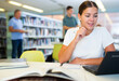 © JackF - Portrait of positive woman with laptop and book in public library