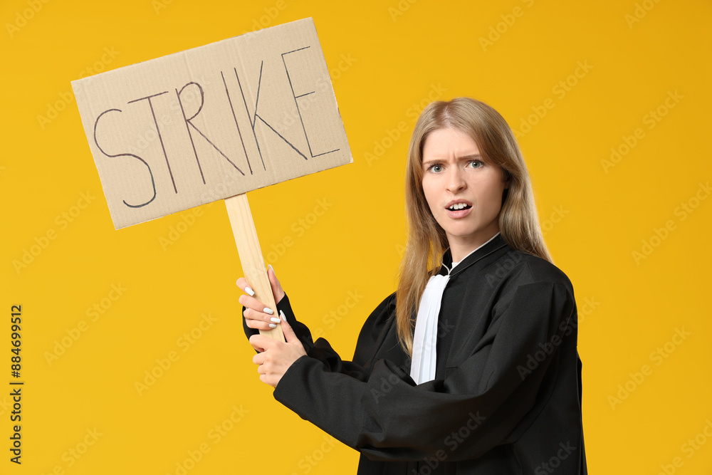 Protesting female judge holding placard with text STRIKE on yellow background