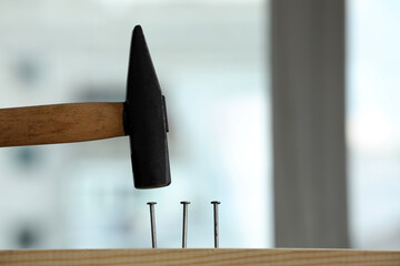 Wall Mural - Hammering nail into wooden surface against blurred background indoors