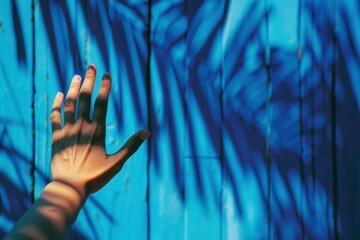 Sticker - Person's hand is shown against a vibrant blue graffiticovered wall, with shadows casting over it