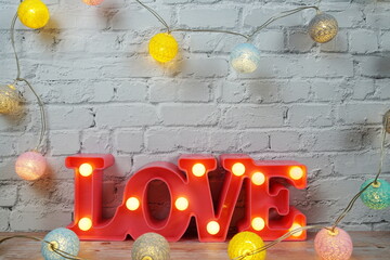 Poster - Love LED sign decorative letters for Valentine's day on white brick wall background