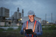 © Kenstocker - Planning engineering with Hard Hat using digital tablet working at Industrial Site on power plant at night time.