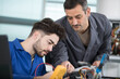 © auremar - supervisor guiding apprentice using a multimeter