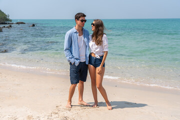 Wall Mural - Happy romantic moment couple enjoying sunny day at the beach, man and woman smile and look relaxed, romance, vacation, beach life, summer holiday relaxation and summer fun, love by the sea concept