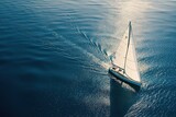 An aerial photo of a sailing yacht in the open sea, with the boat set against the clear blue ocean. Concept for ocean travel and adventure.