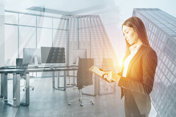 Aufkleber - Attractive young european businesswoman using tablet on blurry office and city double exposure background.