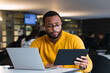 © BUDDHA - Ordinary morning in office. Candid shot of serious young black European employee in spectacles working in office holding generic digital tablet and making notes, looking focused and concentrarted