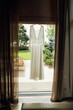 © ruslan_shramko - Beautiful wedding dress hanging near window on clothing rack in room