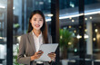 © Minimal Blue - Confident Businesswoman Holding Tablet In Modern Office With Bright Lighting And Glass Windows