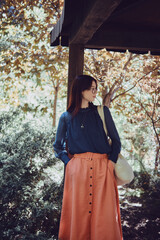 Wall Mural - Teenage girl with a tote bag standing in a wooden garden archway, surrounded by greenery. Stylish and eco-friendly lifestyle portrait. Sustainable living and nature connection concept.