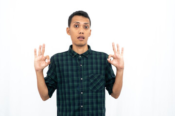 Asian man wearing a green checkered casual shirt stressed showing thumbs up that agree, okay, top. Isolated white background.