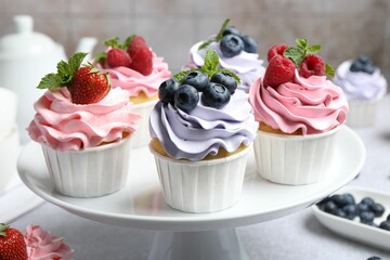 Canvas Print - Tasty cupcakes with different berries on light grey table, closeup