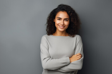 Wall Mural - Confident Young Woman with Curly Hair Smiling and Standing Against a Neutral Gray Background