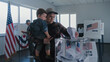 © Framestock - African American man and Caucasian man with child put ballots in box. Multiethnic American voters, people fill out bulletins in voting booths at polling station. Election Day in the USA. Democracy.