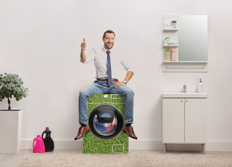 Wall Mural - Businessman in a bathroom sitting on top of eco friendly washing machine