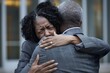 © Rebecca Jestico - Black woman with curly hair in business suit, hugs her husband outside the court building, tears streaming down their faces as they hug each other tightly. The man is wearing a gray suit.