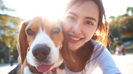 Canvas Print - Young woman taking a selfie with her Beagle dog outdoors in a sunlit park, both smiling and close together.