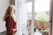 © Westend61 - Blond senior woman looking out through window at home
