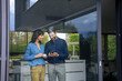 © Westend61 - Happy businesswoman standing with businessman using smart phone at home