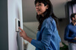 © Westend61 - Smiling businesswoman adjusting thermostat with businessman in background