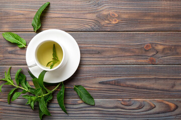 Wall Mural - Cup of mint tea on table background. Green tea with fresh mint top view with copy space