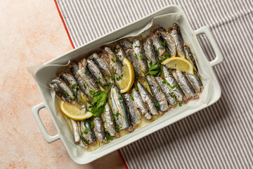 Oven baked italian fish sardoncini or sardines, with olive oil, lemon and parsley. Top view.