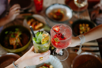 Close-up shot of two cocktails above a filled restaurant table full of food