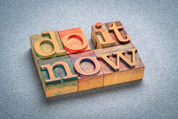 Sticker - do it now - motivational text in retro letterpress wood type stained by color inks, productivity concept